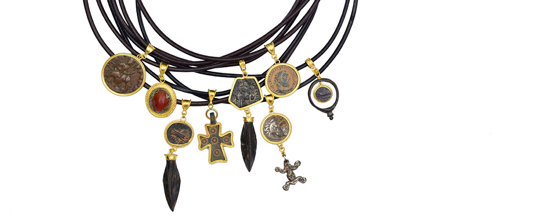 Variety of ancient coins, gemstones and artifacts set in 22k gold on leather cord necklaces.
